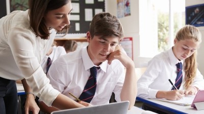 Une enseignante aide les élèves à utiliser un ordinateur en classe